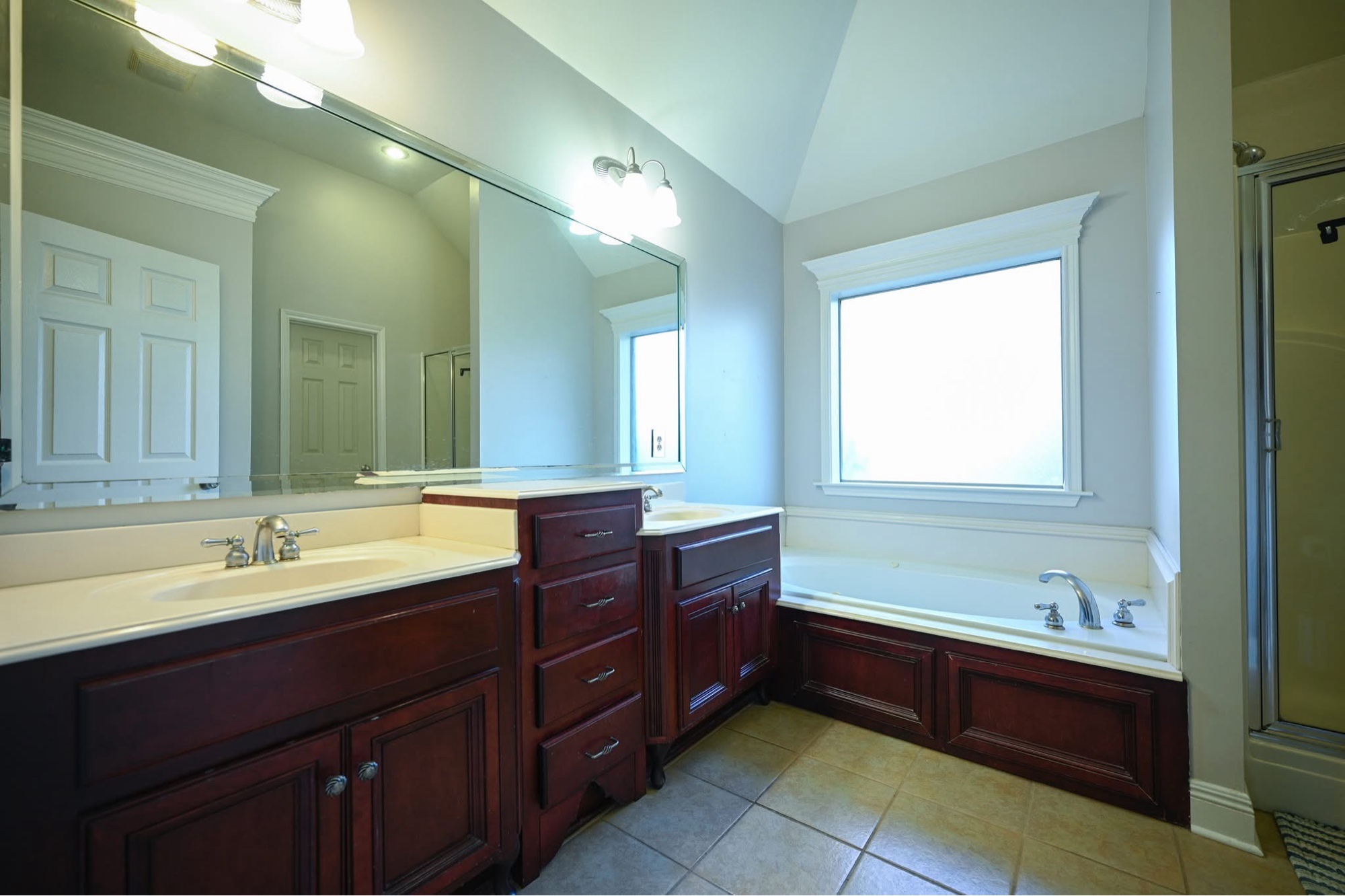 Master bath before — dark cherry vanities and drop-in tub
