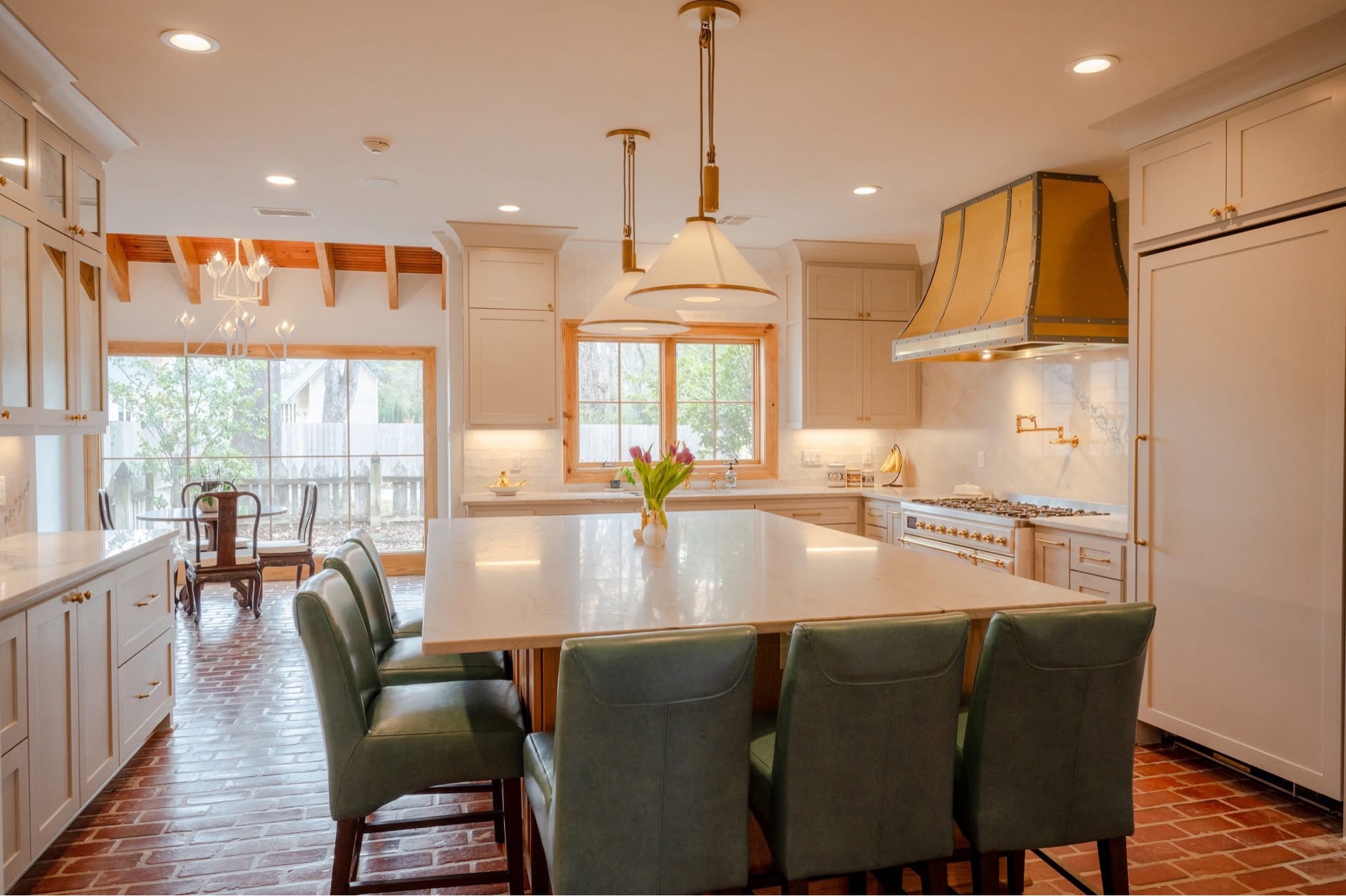 Kitchen after — brass hood, marble island, brick floor