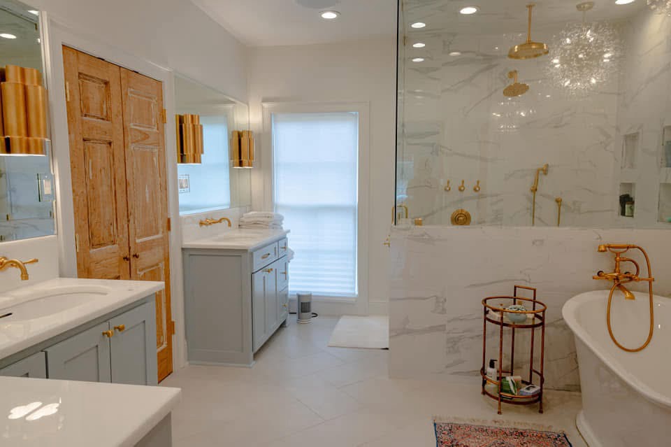 Master bath after — white marble with brass and blue vanities