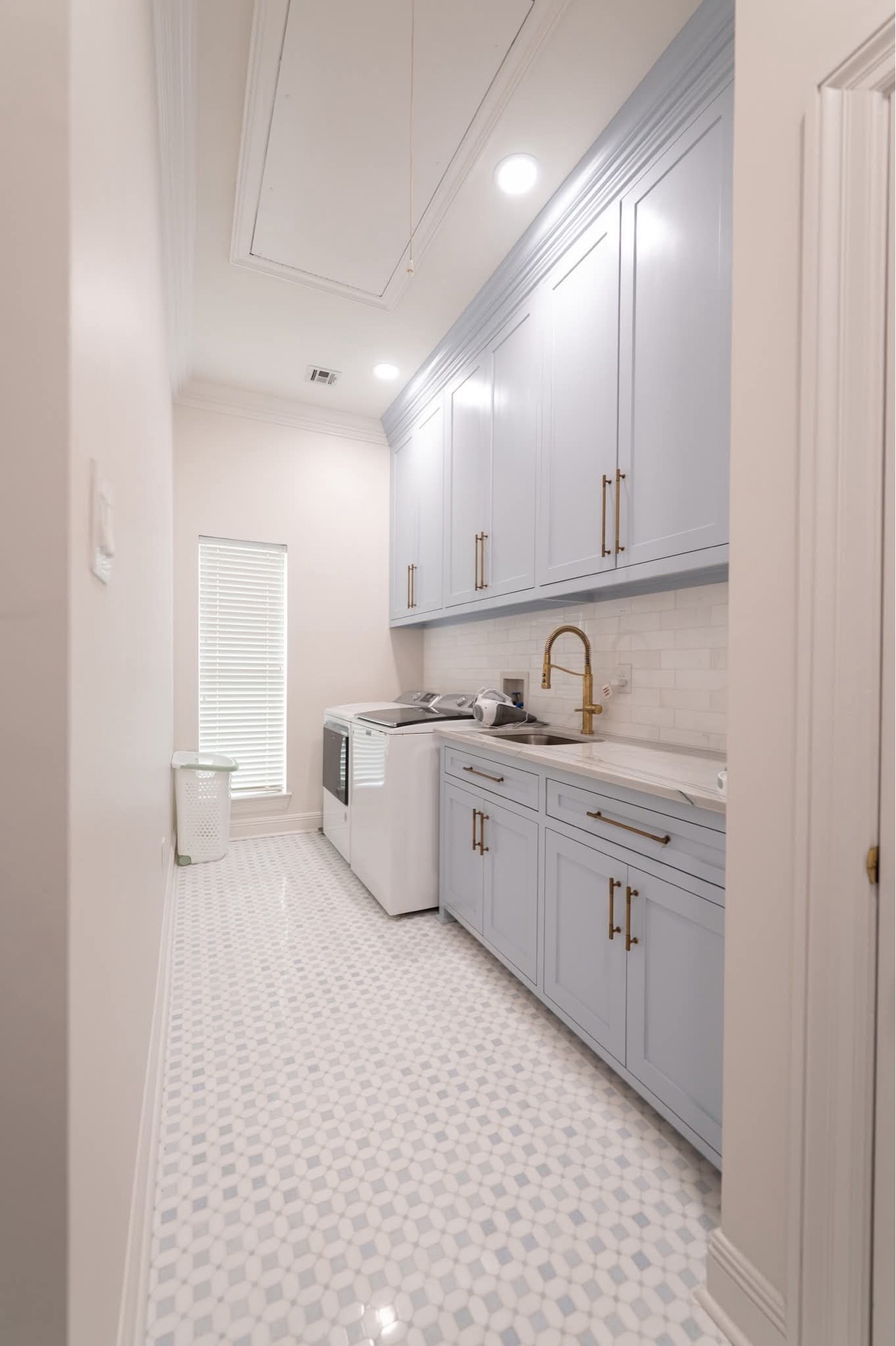 Laundry room with blue-gray cabinets and brass faucet